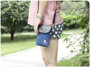 Detail view of the mini canvas crossbody phone bag featuring white rose embroidery and leather flap.