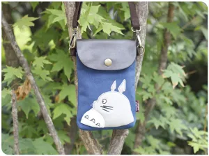 Canvas crossbody bag detail shot, blue fabric with brown leather flap, Totoro embroidery.