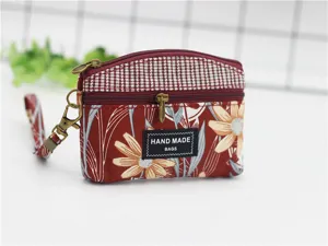 Red floral print coin purse with wrist strap and double zipper, detailed view design.