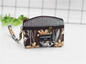 Detailed view of floral print fabric coin purse with double zippers and handy wrist strap.
