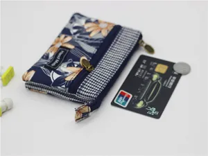 Detail view of multi-layer fabric coin purse with floral pattern and size reference card.