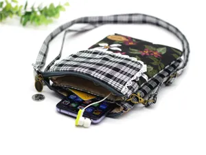 Close-up detail of multi-layer canvas crossbody phone bag with floral and plaid patchwork.