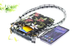 Multi-layer cotton crossbody phone bag detail showing zipper pockets, floral pattern and strap.