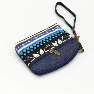 Ethnic style fabric coin purse with double zippers, wrist strap and geometric woven pattern detail.