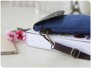 Blue canvas crossbody phone bag featuring a brown leather flap and stylish retro hardware.