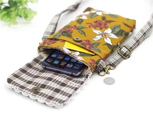 Cotton floral cross-body phone bag with plaid strap, perfect for holding large smartphones.