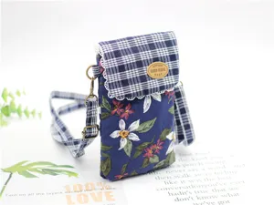 Detail shot of the cotton floral crossbody phone bag with plaid flap and metal hardware.