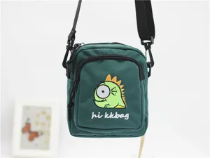 Green nylon cross-body bag detail, cartoon monster embroidery and adjustable strap for daily.