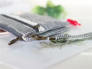 Λεπτομέρειες της γυναικείας τσάντας clutch με φερμουάρ και μοτίβο pied-de-poule σε κοντινό πλάνο.