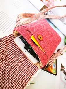 Detailed view of red cotton linen crossbody phone bag with classic plaid strap design.