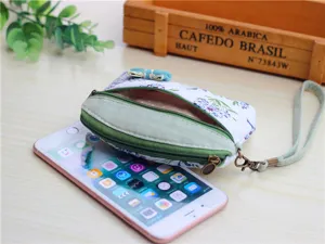 Detailed shot of pastoral floral fabric coin purse with wrist strap and metal zipper.
