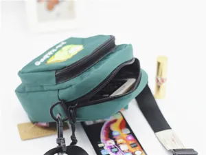 Detailed view of the green nylon crossbody bag featuring cute cartoon embroidery and zip pockets.