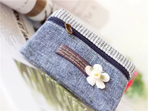 Close-up detail of a blue fabric coin pouch with plaid top and white flower decoration.
