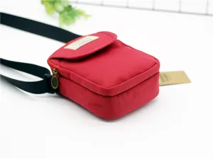 Dettaglio ravvicinato della borsa a tracolla per telefono in nylon rosso con cinturino nero.