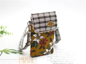 Detailed view of the cotton floral crossbody phone bag featuring a brown plaid flap and strap.