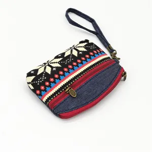 Detailed view of ethnic style canvas coin purse with double zippers and wrist strap.