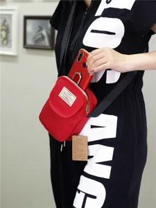 Vista dettagliata della borsa a tracolla rossa in nylon per telefono con tasca e zip.