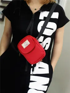 Dettaglio borsa tracolla telefono nylon rosso, design compatto con patta e cinturino.