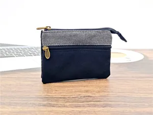 Vista dettagliata del portamonete in tela nero e grigio con vari scomparti con zip.