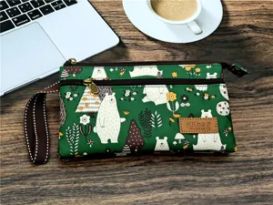 Vue de detail du sac a main vert multicouche avec un joli motif d'ours et une dragonne.