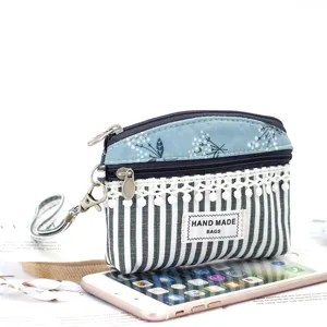 Detailed view of cute fabric coin purse with wrist strap, blue floral pattern and lace trim.
