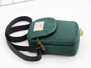 Vista dettagliata della borsa a tracolla in nylon verde scuro, con cerniera ed etichetta in tessuto.