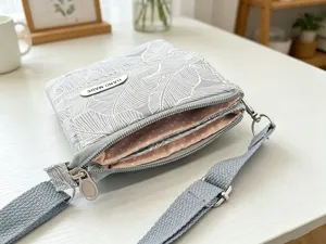 Fabric crossbody phone bag detail view showing multi-layer design with leaf pattern.