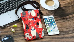 Detailed view of the red waterproof crossbody phone bag with cute cartoon bear print on desk.
