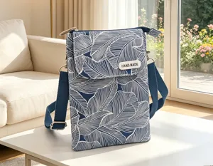 Blue white leaf pattern fabric cross body phone bag detail view with handmade label and strap.