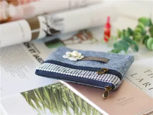 Primo piano del borsellino in denim con doppia cerniera pied-de-poule e decorazione floreale.