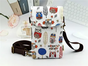 Detail view of the owl and feather pattern crossbody phone bag with adjustable brown strap.
