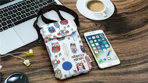 Detailed view of a waterproof owl print crossbody phone bag on a wooden desk lifestyle setup.