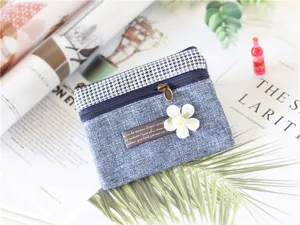 Fabric coin purse detail showing denim texture, houndstooth trim and floral decor.