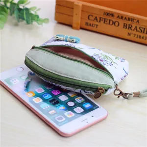 Close-up detail of small floral fabric coin purse with double zippers, bow decor and strap.