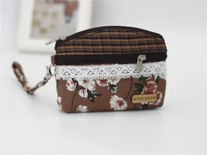 Detailed view of a small floral coin purse with double zippers, wrist strap, and fabric design.