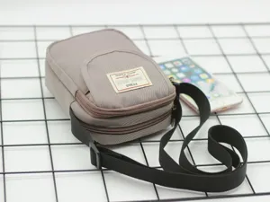Vista dettagliata della borsa a tracolla grigia in nylon, con zip ed etichetta.