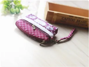 Detailed view of a vintage floral fabric coin purse with double zippers and wrist strap.