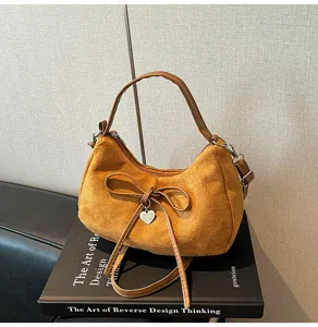 Bruine suède schoudertas met elegante strik en hartvormige hanger, stijlvolle crossbody tas.