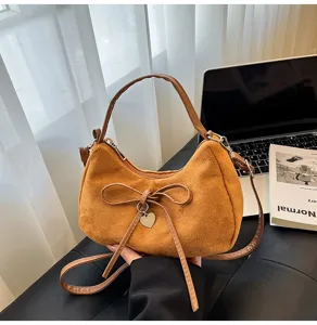 Bruine suède schoudertas met strik en hartvormige hanger, elegante crossbody tas voor dagelijks woon-werk.