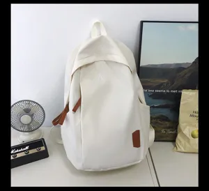 Casual minimalist white canvas backpack with brown leather accents and front pocket detail.