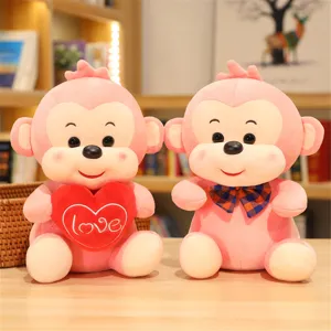 Close-up detail of cute pink plush monkey toys with heart embroidery and bow tie design.