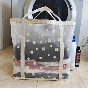 Detalle de la cesta de ropa de malla con tejido transpirable, estampado de margaritas y asas.