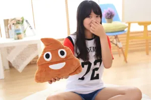 Detail view of funny poop plush pillow showing embroidered cute face and soft brown plush fabric.