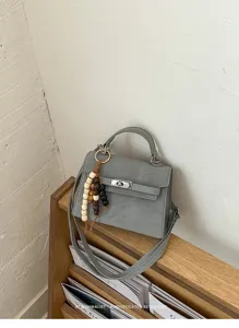 Chic grey top handle crossbody bag featuring a turn-lock closure and stylish wooden bead charm.