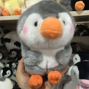 Close-up of a cute round plush penguin toy with soft grey and white fur and orange feet.