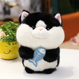 Lindo gato de peluche en blanco y negro sosteniendo un pez azul, suave juguete.