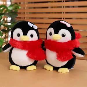 Simpatico peluche pinguino con sciarpa rossa e fiocco, morbido animale di stoffa per bambini.