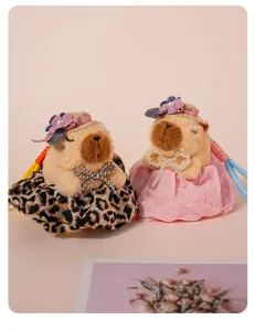 Dettaglio ciondolo peluche capibara carino con vestito grazioso e cappello di paglia.