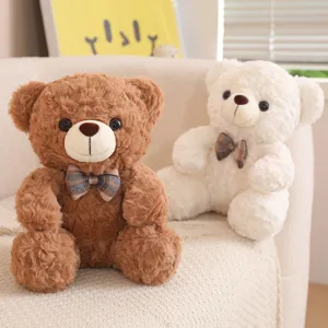 Close-up detail of cute sitting brown and white teddy plush bears with checkered bows on sofa.
