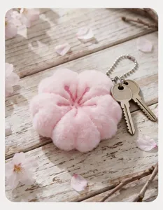 Primer plano detallado del colgante de llavero de felpa con flor de cerezo rosa en la mesa.